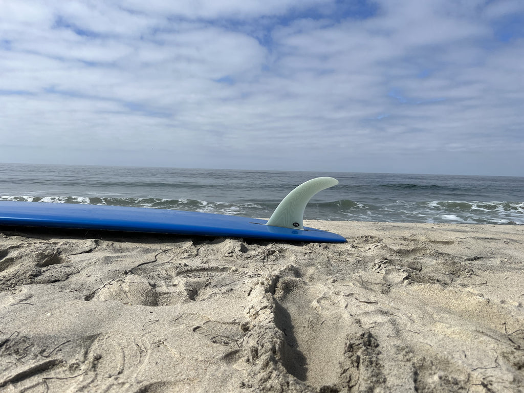 Bing Drive fin in a blue surfboard on the beach.