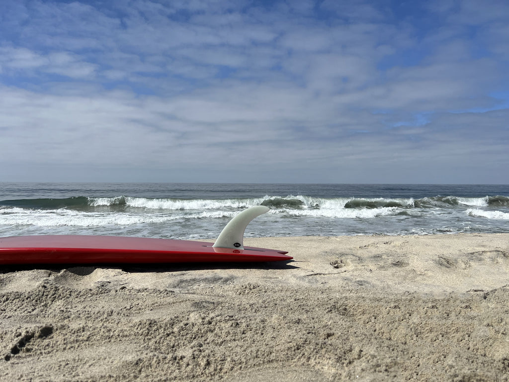 Bing Mid Single fin in a red surfboard on the beach.