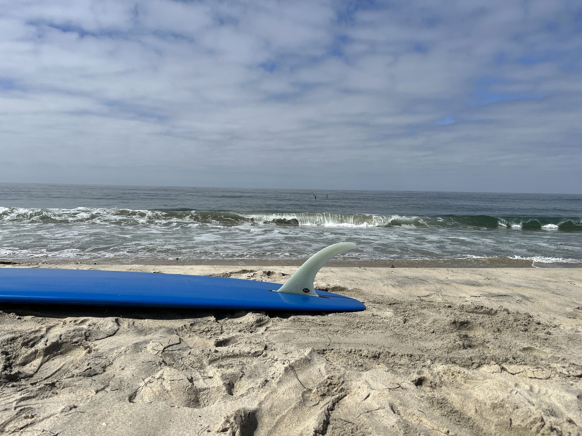 Bing Speed fin in a blue surfboard on the beach.