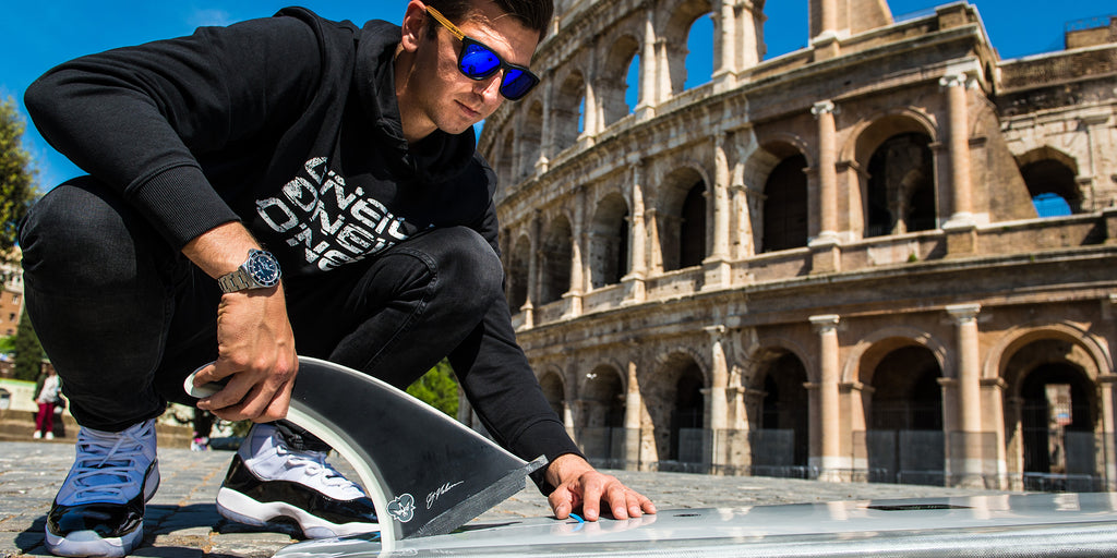 Marco "Bosko" Boscaglia putting a CJ Power Flex fin into his longboard in front of the Colosseum in Rome, Italy.